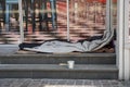 Sleeping bag of a homeless person spread on the stairs in front of a modern posh lounge or restaurant.