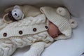 Sleeping beautiful 2 month old baby girl in a white knitted suit lies in her white crib