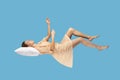 Sleeping woman floating in air. lying on pillow levitating, flying in dream with hands up to catch. Royalty Free Stock Photo