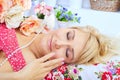 Sleeping blond woman lying on pillow among flowers