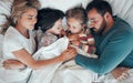 Sleeping caucasian family of four in pyjamas from above lying cosy together in bed at home. Loving parents cuddling two Royalty Free Stock Photo