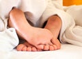 Sleeping child dirty feet on white bed linen from backside. Royalty Free Stock Photo