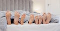 Sleeping feet, relax and family in bed with love, bond or security at home together. Barefoot, children or parents in a