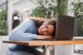 Sleeping girl with laptop on the table outdoor in cafe. Tired young woman have a break at work and sleeping and relaxing Royalty Free Stock Photo