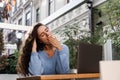 Sleeping girl with laptop is yawning outdoor on terrace in cafe. Tired young woman have a break at work and sleeping and Royalty Free Stock Photo