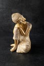 Sleeping golden color Buddha statuette on black stone background. Spa or meditation concept. Retro style Royalty Free Stock Photo