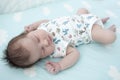 Sleeping infant dressed romper suit, baby lying on bedsheet with closed eyes Royalty Free Stock Photo