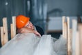 Sleeping on a job. Taking a break. Industrial worker indoors in factory. Young technician with orange hard hat Royalty Free Stock Photo