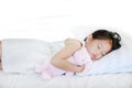 Sleeping little Asian kid girl lying on bed with hugging doll