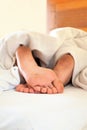 Sleeping little child funny dirty feet on white bed linen Royalty Free Stock Photo