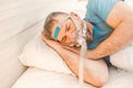 Sleeping man with chronic breathing issues considers using CPAP machine in bed. Royalty Free Stock Photo