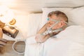 Sleeping man with chronic breathing issues considers using CPAP machine in bed.