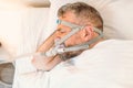 Sleeping man with chronic breathing issues considers using CPAP machine in bed.