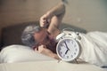 Sleeping man disturbed by alarm clock early morning. Angry man in bed awoken by a noise Royalty Free Stock Photo