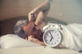 Sleeping man disturbed by alarm clock early morning. Angry man in bed awoken by a noise Royalty Free Stock Photo