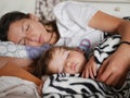 Sleeping mother hugged a sleeping baby. Mother and her little son sleep in a large bed, hiding in a blanket Royalty Free Stock Photo