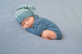 Sleeping newborn baby in blue jumpsuit and hat