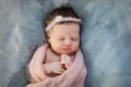 Sleeping newborn baby girl swaddled in knitted pink plaid on soft blue background Royalty Free Stock Photo