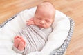 Sleeping newborn baby in the gray basket on the light wooden background. Pregnancy, birth, maternity leave, IVF concept