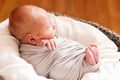 Sleeping newborn baby in the gray basket. Small hands and feet of the child. Baby wrapping