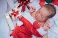 Sleeping newborn baby on mother hand in Christmas hat with gift Royalty Free Stock Photo