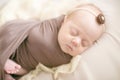 Sleeping newborn baby in a wrap brown blanket on  bed Royalty Free Stock Photo