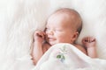 Sleeping smiling newborn baby in a wrap on white blanket. Royalty Free Stock Photo