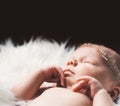 Sleeping newborn baby in a wrap on white blanket. Royalty Free Stock Photo