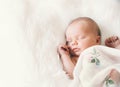 Sleeping newborn baby in a wrap on white blanket. Royalty Free Stock Photo