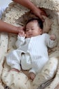 Sleeping newborn infant baby boy lying down on beautiful crib basket on bed, little child sleeping, parent hand gentle touch him, Royalty Free Stock Photo