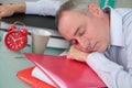 Sleeping in office with alarm clock on side Royalty Free Stock Photo