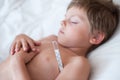 Sleeping sick little child with thermometer in armpit