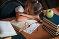 Sleeping on the table. Cute little girl with pigtails is in the library. Apple on the books Royalty Free Stock Photo