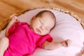 Sleeping ten-day-old baby girl in pink bodysuit. photo shoot of newborns