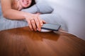 sleeping woman in bed cellphone charging on wireless charger