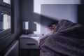 Sleeping woman in bed at night in dark bedroom. Person resting. Asleep under cover and blanket. Cold room at home. Royalty Free Stock Photo