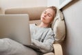 Sleeping woman in gray home suit with laptop