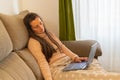 Sleeping woman sitting on a sofa and covered with a blanket while working on the laptop. Tired woman working from home on her Royalty Free Stock Photo