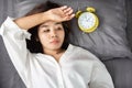 Sleepless Asian woman insomnia,overthinking lying down in bed with alarm clock show the time late at night Royalty Free Stock Photo