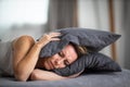 Sleepless lady covering ears with pillow Royalty Free Stock Photo