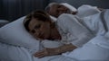 Sleepless lady lying in bed turned back to man suffering menopause, woman health Royalty Free Stock Photo