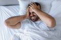 Sleepless man lying in bed touching aching head at home Royalty Free Stock Photo