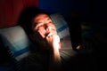 Sleepless and thinking man using his mobile phone in bed in the dark. Royalty Free Stock Photo