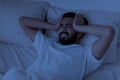 Sleepless indian guy suffering acute headache while lying in bed at night Royalty Free Stock Photo