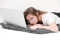 Sleeps in the workplace. Tired young woman working, headache, falling asleep on white background. Learns, using laptop computer on Royalty Free Stock Photo