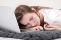 Sleeps in the workplace. Tired young woman working, headache, falling asleep on white background. Learns, using laptop computer on Royalty Free Stock Photo