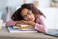 Sleepy african-american teen girl resting head on paper books, tired of school, studying and reading Royalty Free Stock Photo