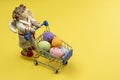 A sleepy Angel carries colorful Easter eggs in a shopping basket