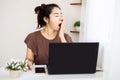 Sleepy Asian woman worker yawning and tired working late from home office