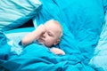 Sleepy baby in the crib with blue bedding Royalty Free Stock Photo